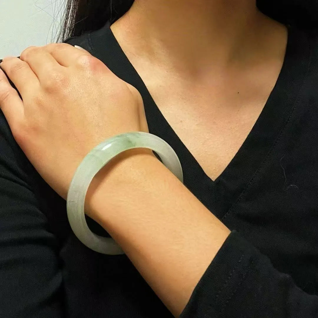 Bracelet jonc en calcédoine verte pâle, porté au poignet d'une femme.