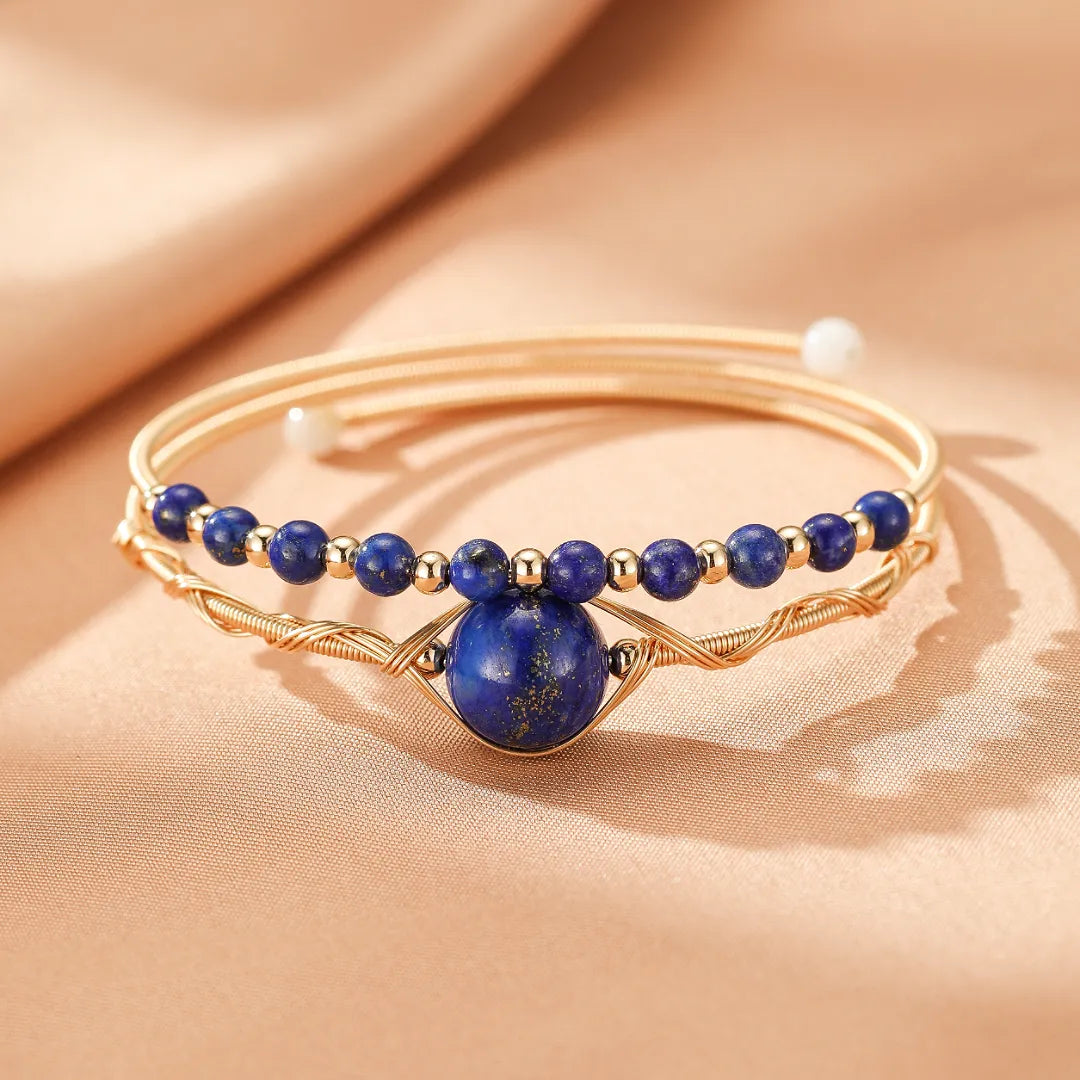 Bracelet jonc doré avec des perles de lapis-lazuli et une pierre centrale en lapis-lazuli sculptée en œil protecteur.