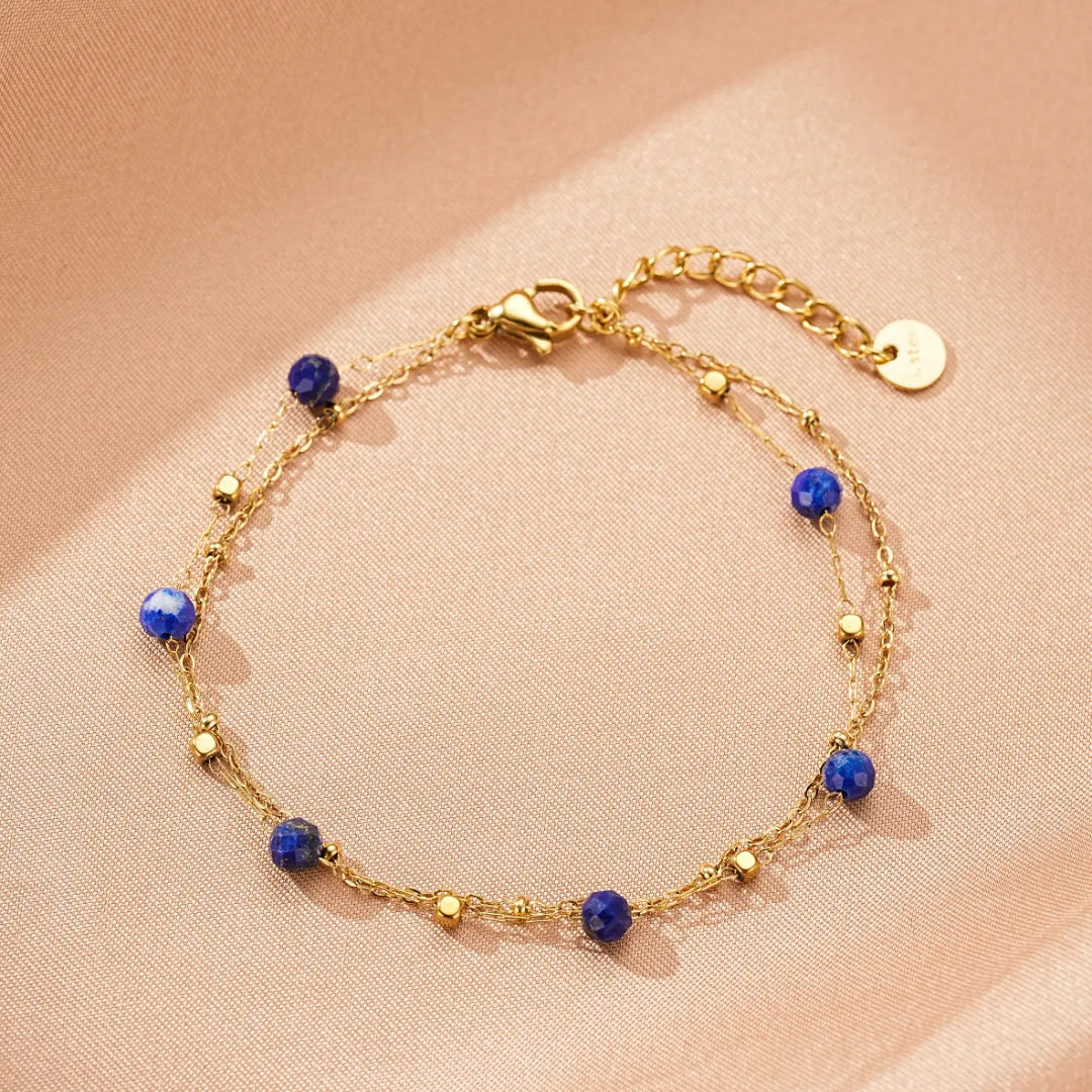 Bracelet fin en plaqué or avec des pierres de lapis-lazuli bleues et de petites perles dorées.
