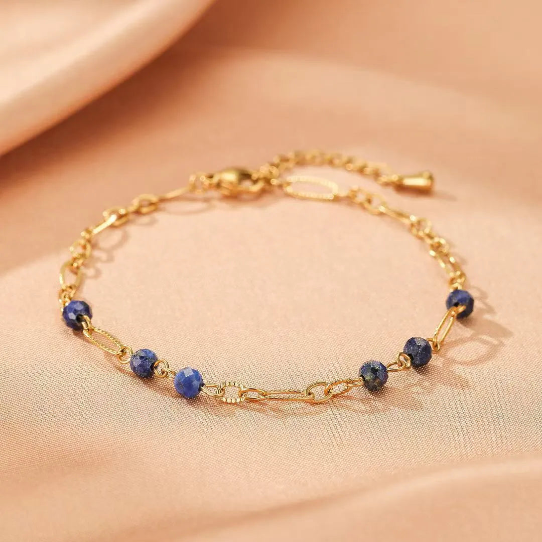 Bracelet en lapis-lazuli "Reflets Étoilés" avec une chaîne dorée et des perles bleues facettées disposées le long de la chaîne.