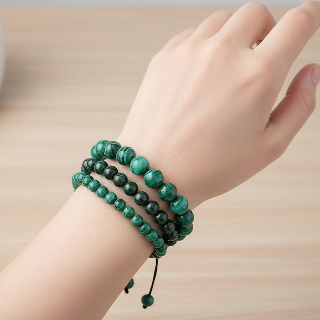 Trois bracelets en malachite de différentes tailles portés sur un poignet, le plus grand bracelet est à l'extérieur et le plus petit est à l'intérieur.