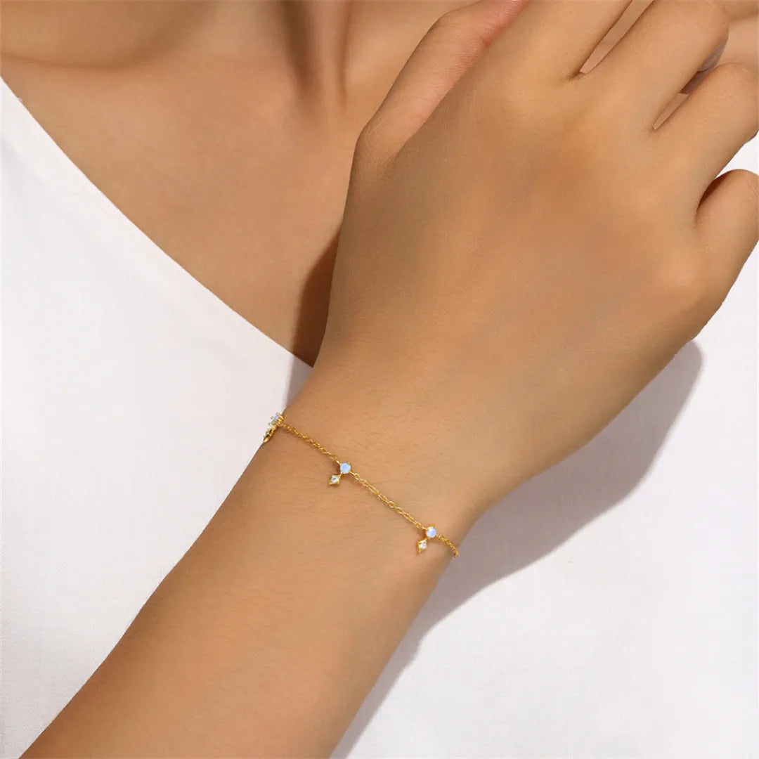 Bracelet fin en argent doré or avec opales et zircons cubiques, le bracelet "Éclat Étoilé" est porté au poignet d'une femme.
