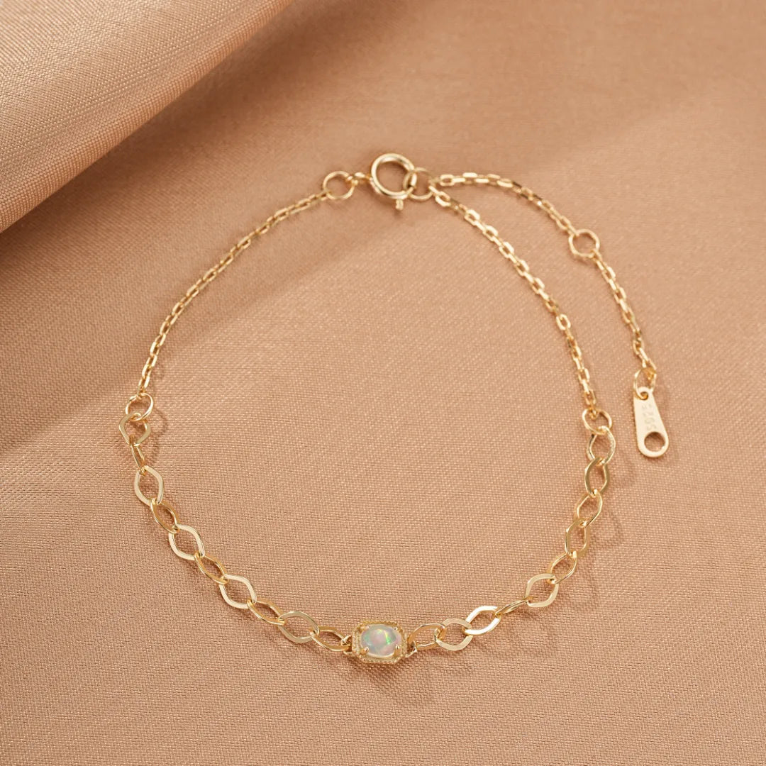 Bracelet fin en argent doré à l'or, orné d'une opale rectangulaire centrale "Reflets Magiques", sur fond beige.