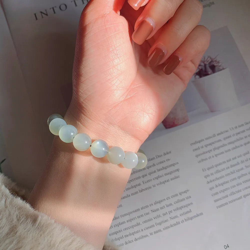 Bracelet "Élégance Lunaire" avec des perles rondes en pierre de lune blanche sur le poignet d'une femme.