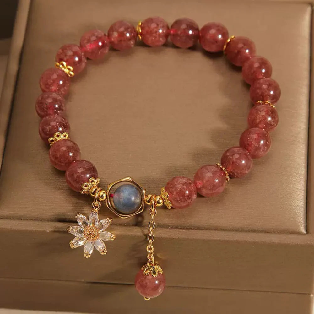 Bracelet "Fleur Mystérieuse" en quartz fraise et cristal de roche, orné d'une fleur en zircon et d'une pierre bleue hexagonale.