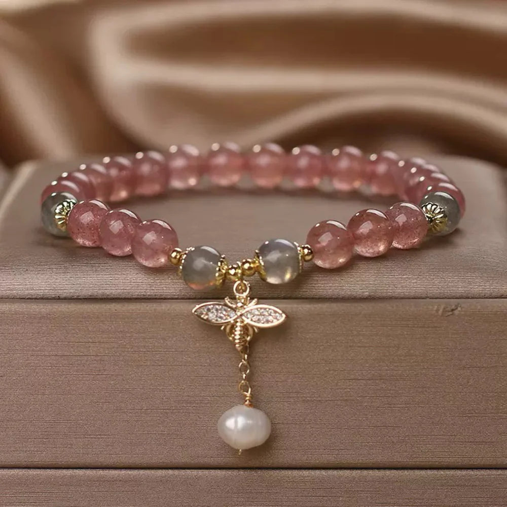 Bracelet "Douceur Abeille" fait de perles de quartz fraise roses, de labradorite grises et d'un pendentif abeille orné de strass, avec une perle d'eau douce blanche.