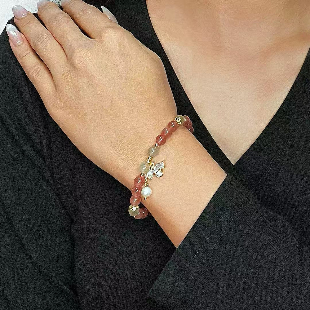 Bracelet "Douceur Abeille" en quartz fraise, labradorite, perle et breloque papillon sur un poignet féminin