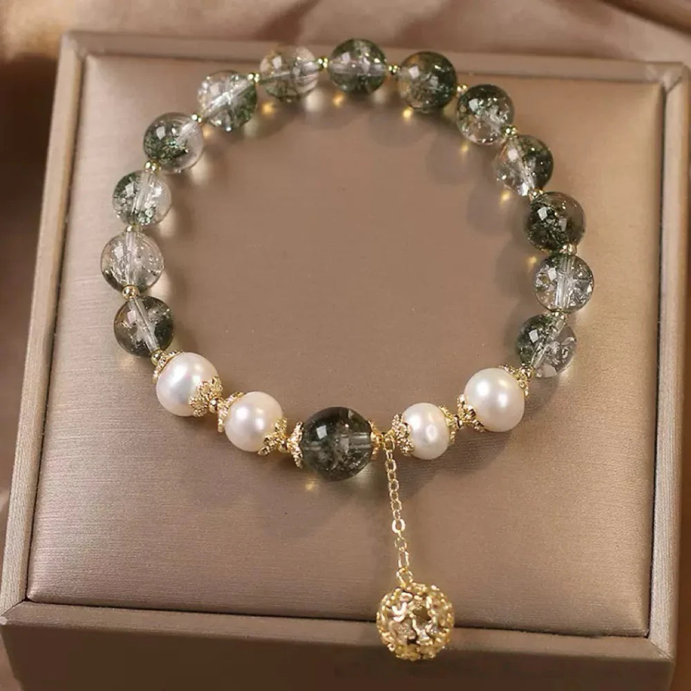 Bracelet en quartz vert et perles nacrées avec une sphère ajourée dorée en pendentif.
