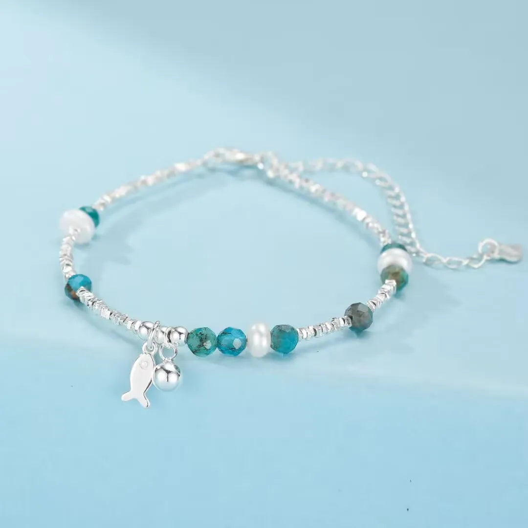 Bracelet "Charme Poisson" en argent 925 avec des pierres topaze bleues et des perles blanches.