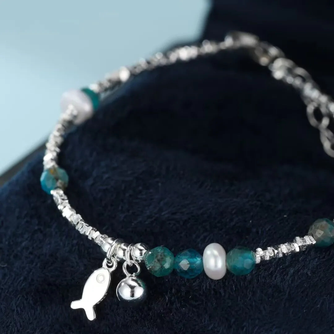 Bracelet en argent 925 avec des pierres de topaze bleue, une perle blanche et un charmant pendentif poisson.