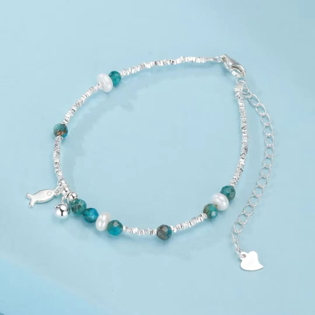 Bracelet en argent 925 avec des perles de topaze bleue, des perles d'eau douce blanches et un charm poisson argenté.