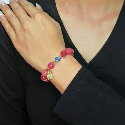 Bracelet "Raffinement Impérial" en tourmaline rose et cristal de roche, orné d'une breloque dorée et de perles bleues et dorées.