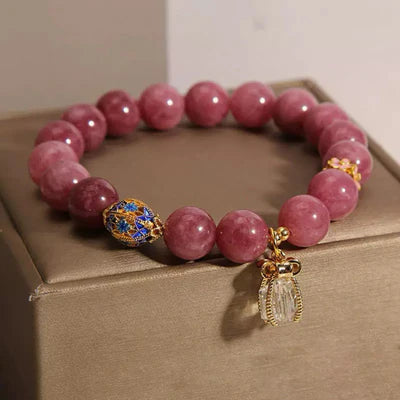 Bracelet "Raffinement Impérial" en tourmaline rose et cristal de roche avec un pendentif en cristal et un fermoir orné de motifs bleus et dorés.