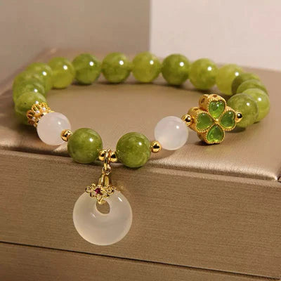 Bracelet "Rayons d'Optimisme" en tourmaline verte et jade avec un pendentif trèfle doré et une breloque jade circulaire.