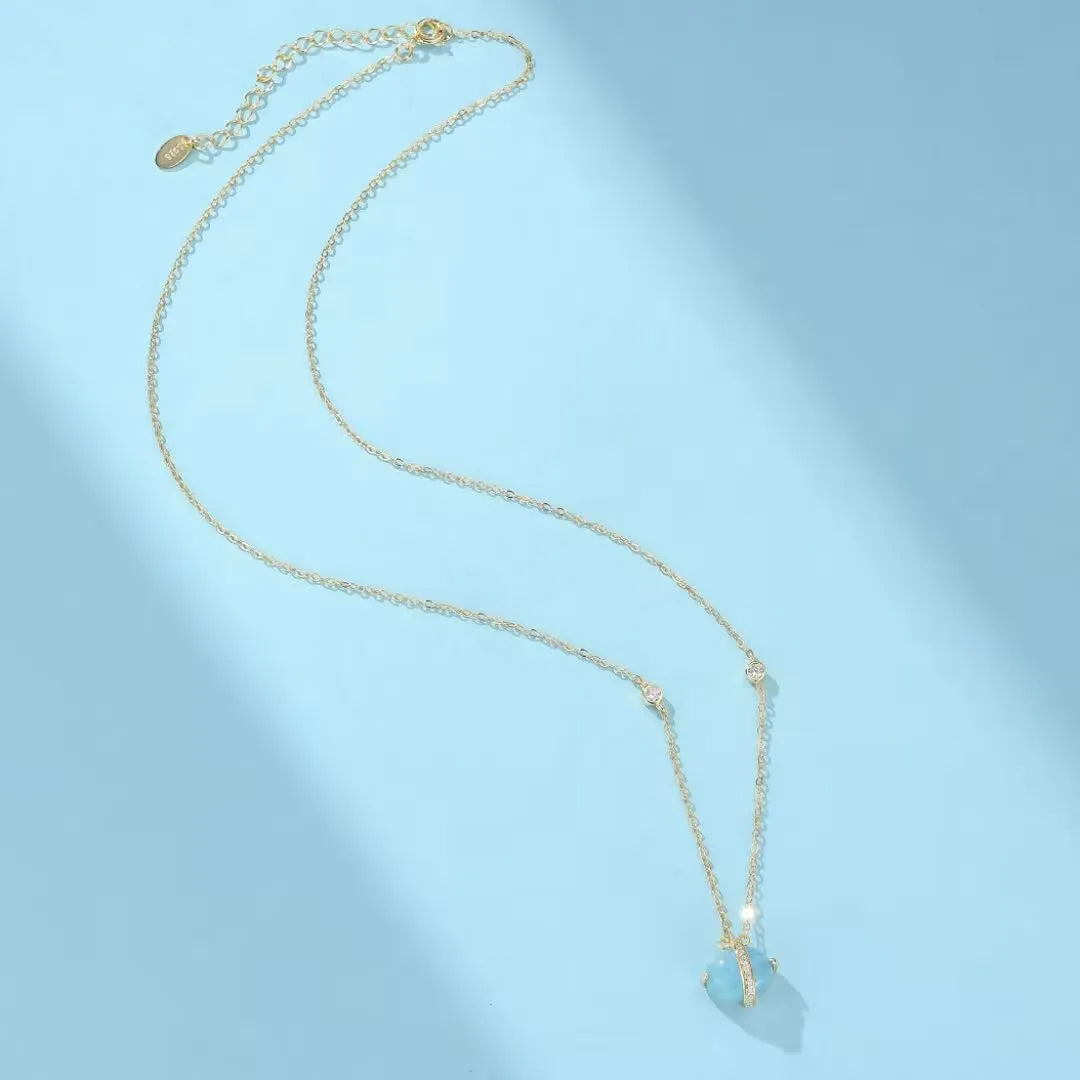 Collier "Galaxie Bleue" avec pendentif en aigue-marine bleue et chaîne en argent doré or 14K, orné de petites pierres scintillantes.