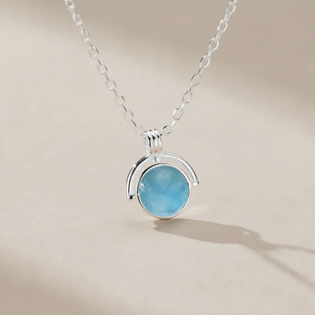 Collier "Mystère d'Océan" en argent 925 avec une pierre d'aigue-marine bleue claire ronde et lumineuse, suspendu à une fine chaîne en argent.