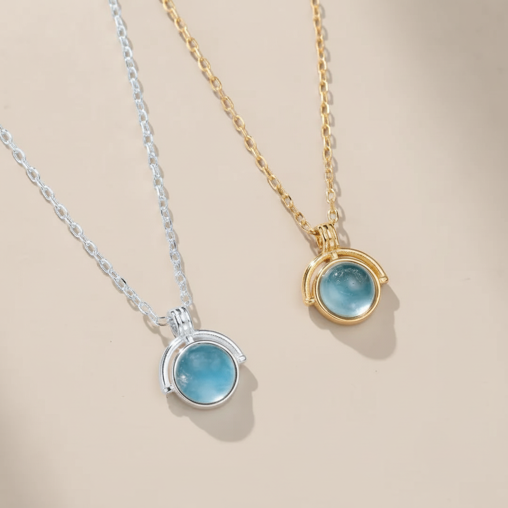 Deux colliers, un en argent et l'autre en plaqué or, ornés d'une pierre bleue ronde ressemblant à de l'aigue-marine, suspendus à des chaînes délicates.