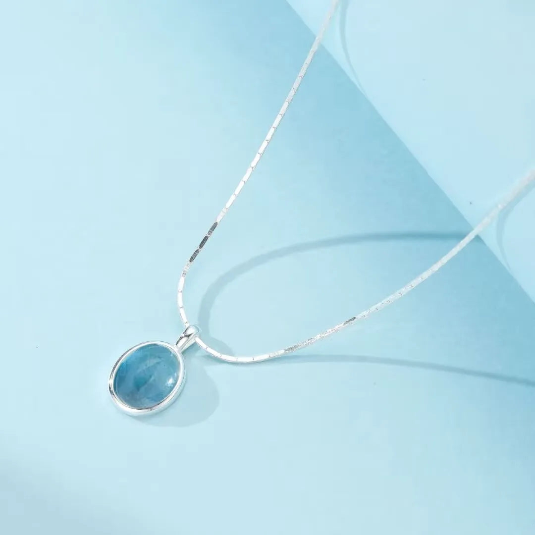 Collier en argent 925 serti d'une pierre d'aigue-marine ovale bleue, monté sur une fine chaîne serpent.