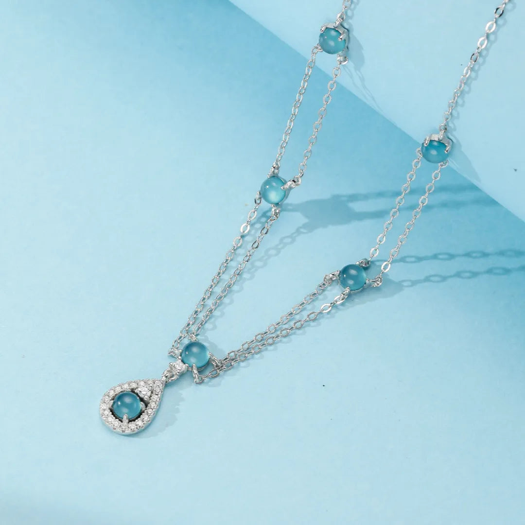 Collier en argent avec des perles bleues d'aigue-marine et un pendentif en forme de goutte serti de zirconiums.