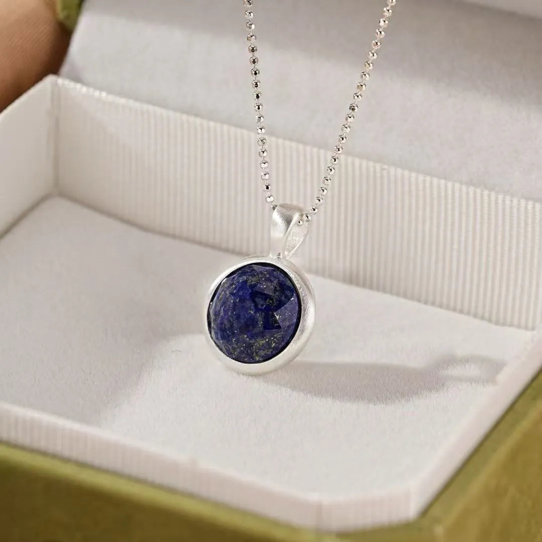 Collier "Profondeur Céleste" en argent avec un pendentif rond en lapis-lazuli bleu profond, monté sur une chaîne à billes argentée.