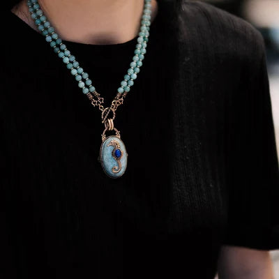 Collier double rang en amazonite avec un pendentif ovale orné d'un hippocampe bleu saphir et d'une pierre de lune, fermoir mousqueton doré.