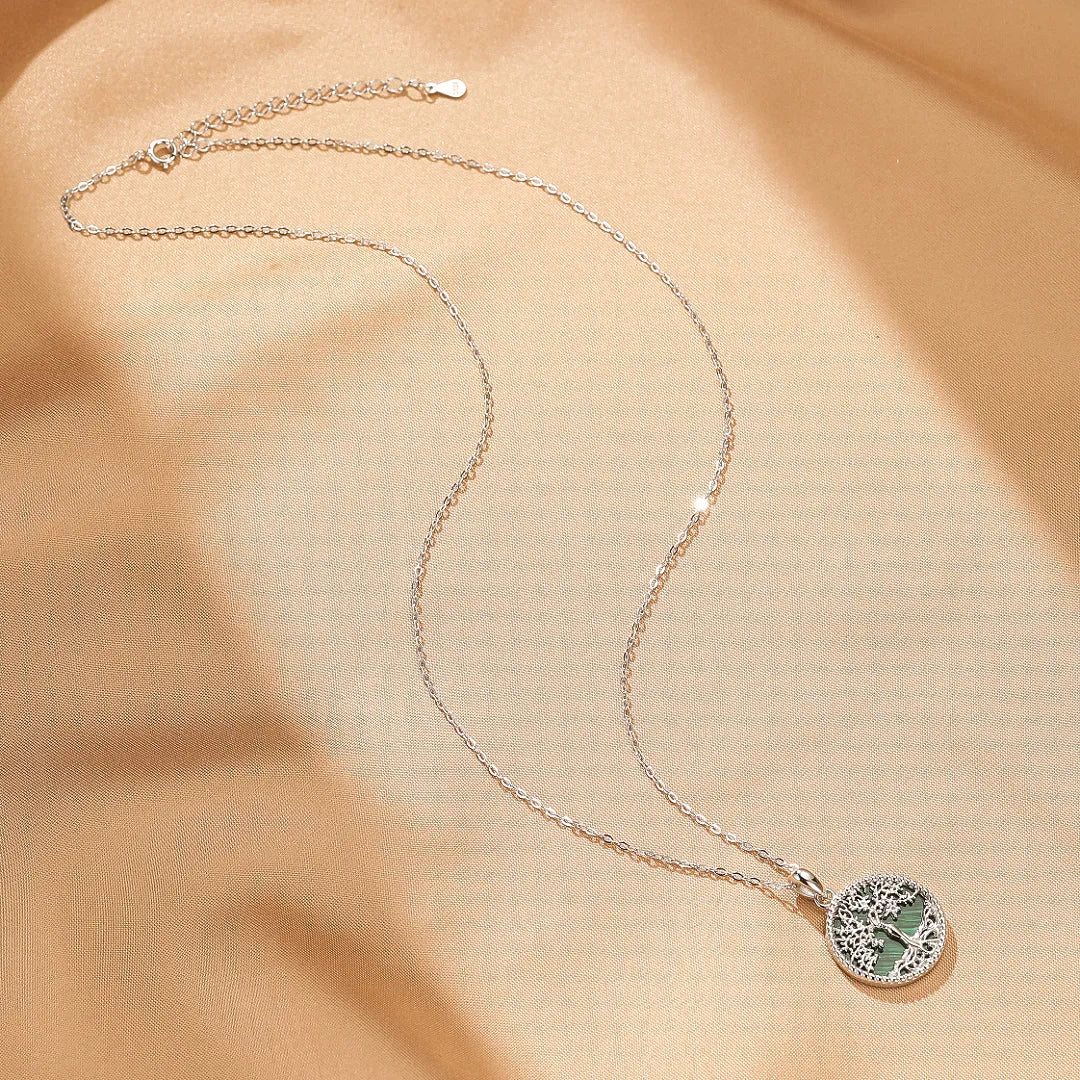 Collier Arbre de Vie Malachite "Racines d'Équilibre" en argent sur un fond satiné doré.