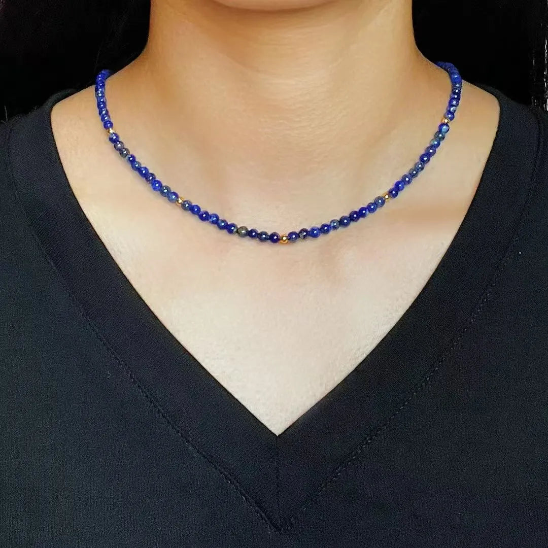 Collier ras du cou "Beauté Astrale" fait de petites perles de lapis-lazuli bleues et de quelques perles dorées, porté par une femme.