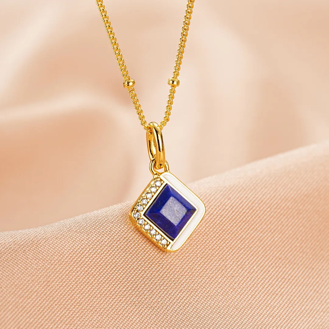 Collier "Élégance Raffinée" en argent doré, orné d'un pendentif carré en lapis lazuli bleu profond, bordé de petits zircons scintillants et d'un contour blanc émaillé.