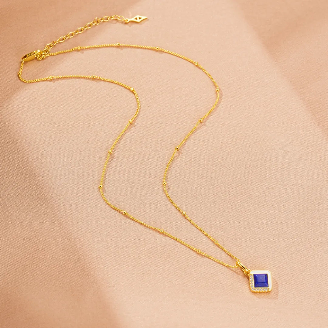 Collier "Élégance Raffinée" en argent doré or, orné d'un pendentif carré bleu lapis lazuli entouré de petites pierres scintillantes, sur une chaîne fine et délicate.