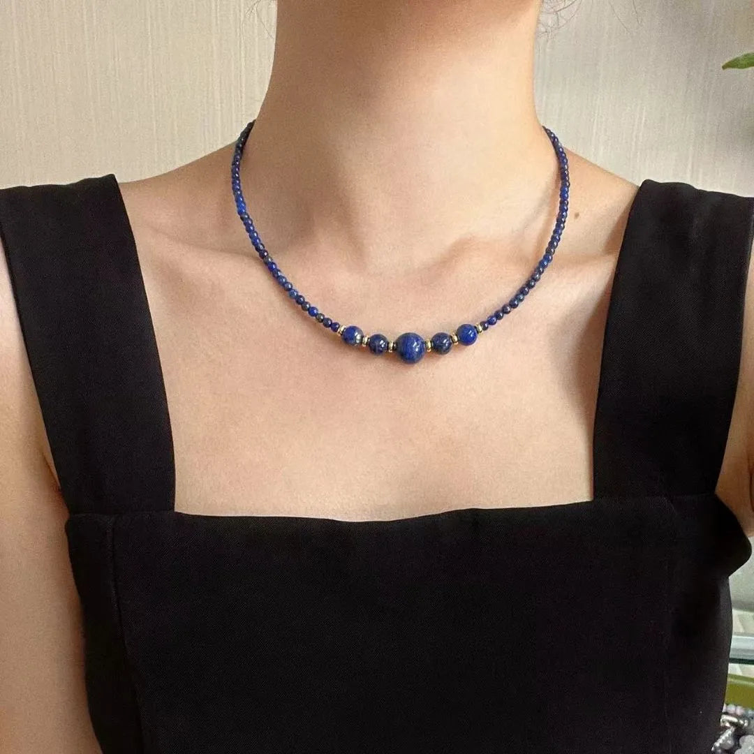 Collier "Équilibre Doux" en Lapis Lazuli avec des perles de différentes tailles et des accents dorés, porté par une femme.