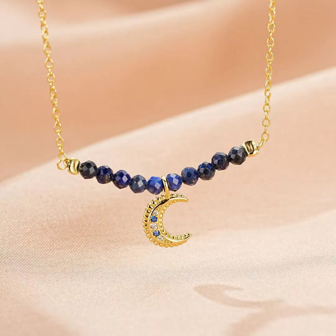 Collier "Nuit Sage" en argent doré à l'or 18 carats, orné de perles de lapis-lazuli et d'un pendentif croissant de lune serti de zirconias et de saphirs.