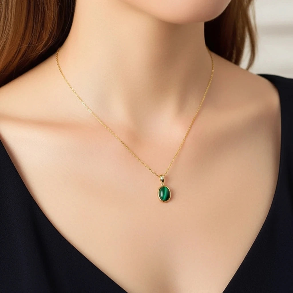 Collier Aura Antique en argent doré avec une pierre de malachite verte ovale au centre, porté par une femme.
