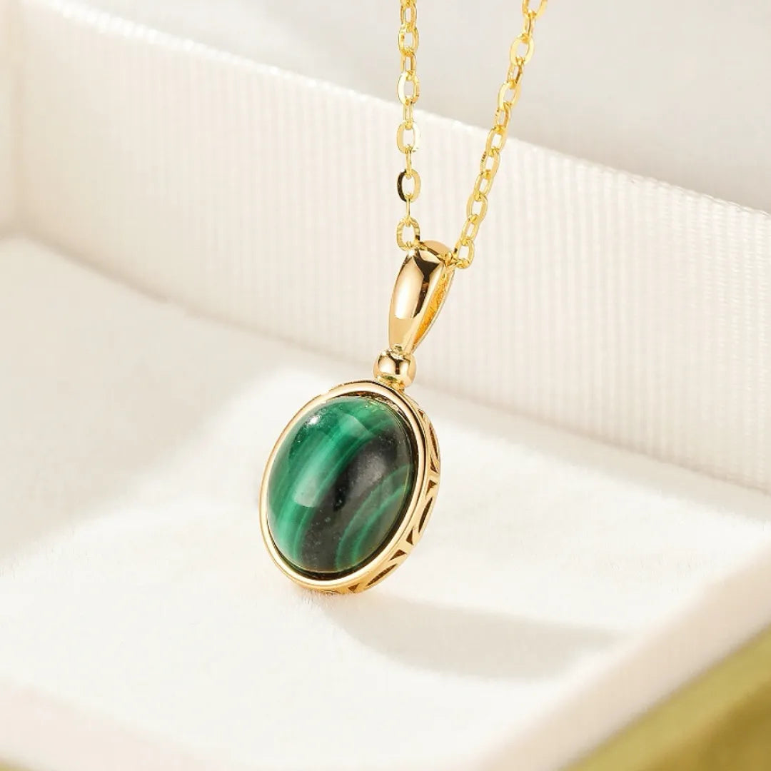 Collier "Aura Antique" en argent doré avec un pendentif ovale en malachite verte aux motifs striés et une monture ajourée travaillée.