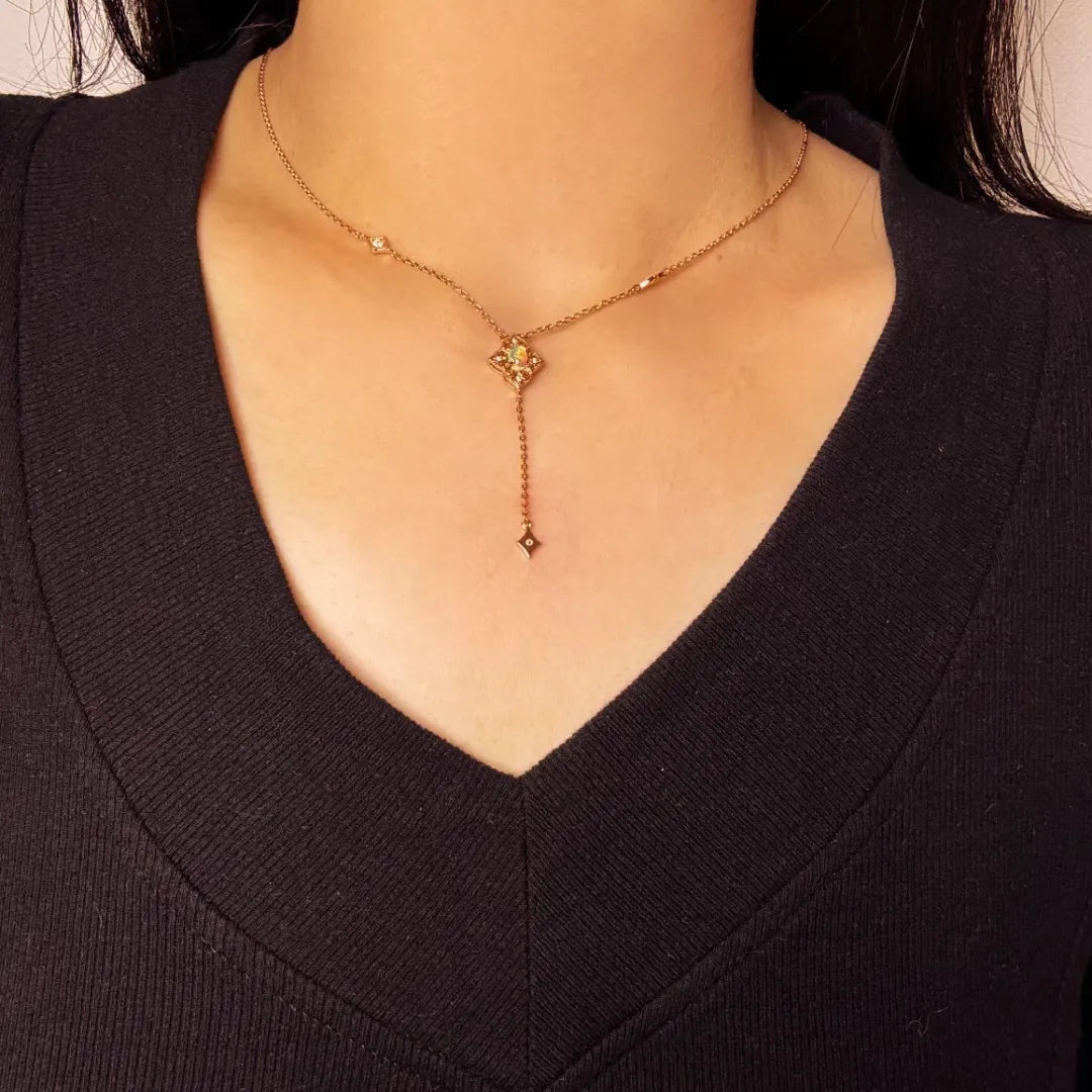 Collier en argent doré à l'or avec un pendentif opale en forme de fleur stylisée et une petite breloque tombante, orné de petits cristaux sur la chaîne.