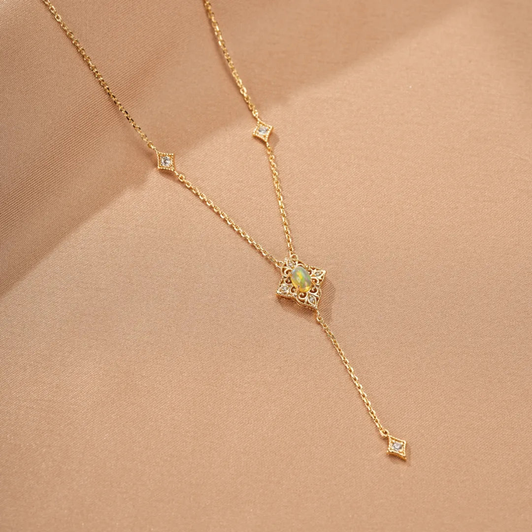 Collier en argent doré à l'or avec une opale au centre d'une étoile ornée de diamants et d'autres petits diamants le long de la chaîne.