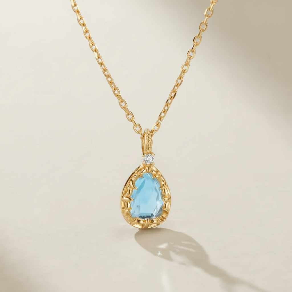 Collier "Éclat Marin" en argent 925 doré à l'or 14 carats, orné d'une topaze bleue en forme de poire et d'un petit diamant serti.