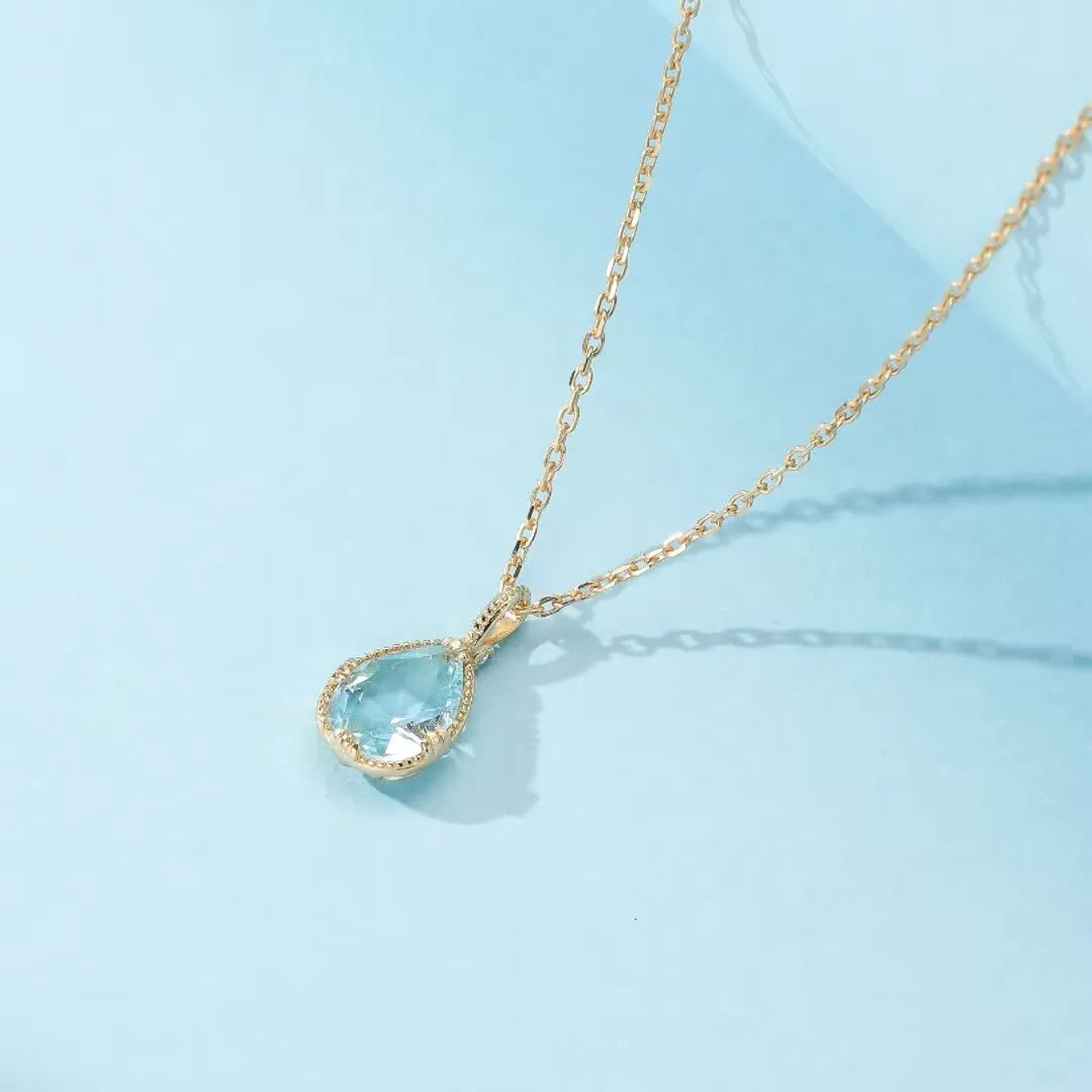 Collier "Éclat Marin" en argent 925 doré à l'or 14K avec une topaze bleue en forme de poire sertie sur une chaîne délicate.