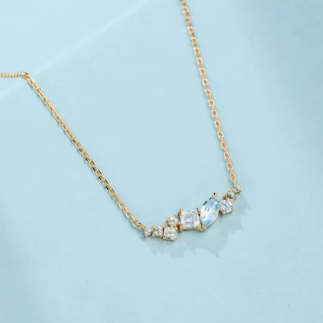 Collier "Élégance Royale" en argent 925 doré à l'or 14K, orné de topazes bleues et de cristaux clairs de formes variées disposés en arc sur une chaîne délicate.