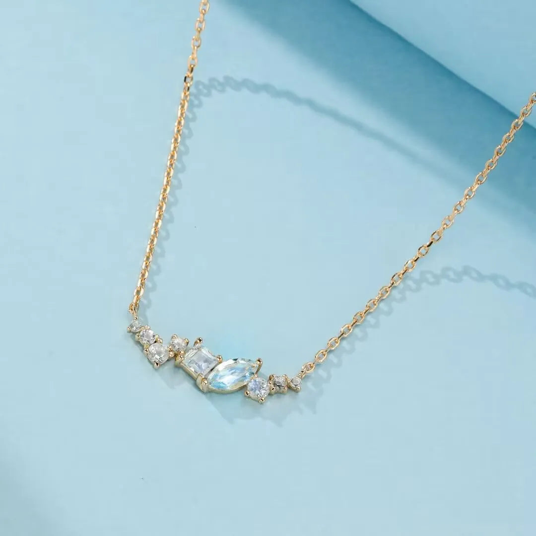 Collier fin en argent 925 doré à l'or 14K, orné d'une grappe de pierres bleues et blanches de différentes formes, dont une topaze centrale en forme de marquise.
