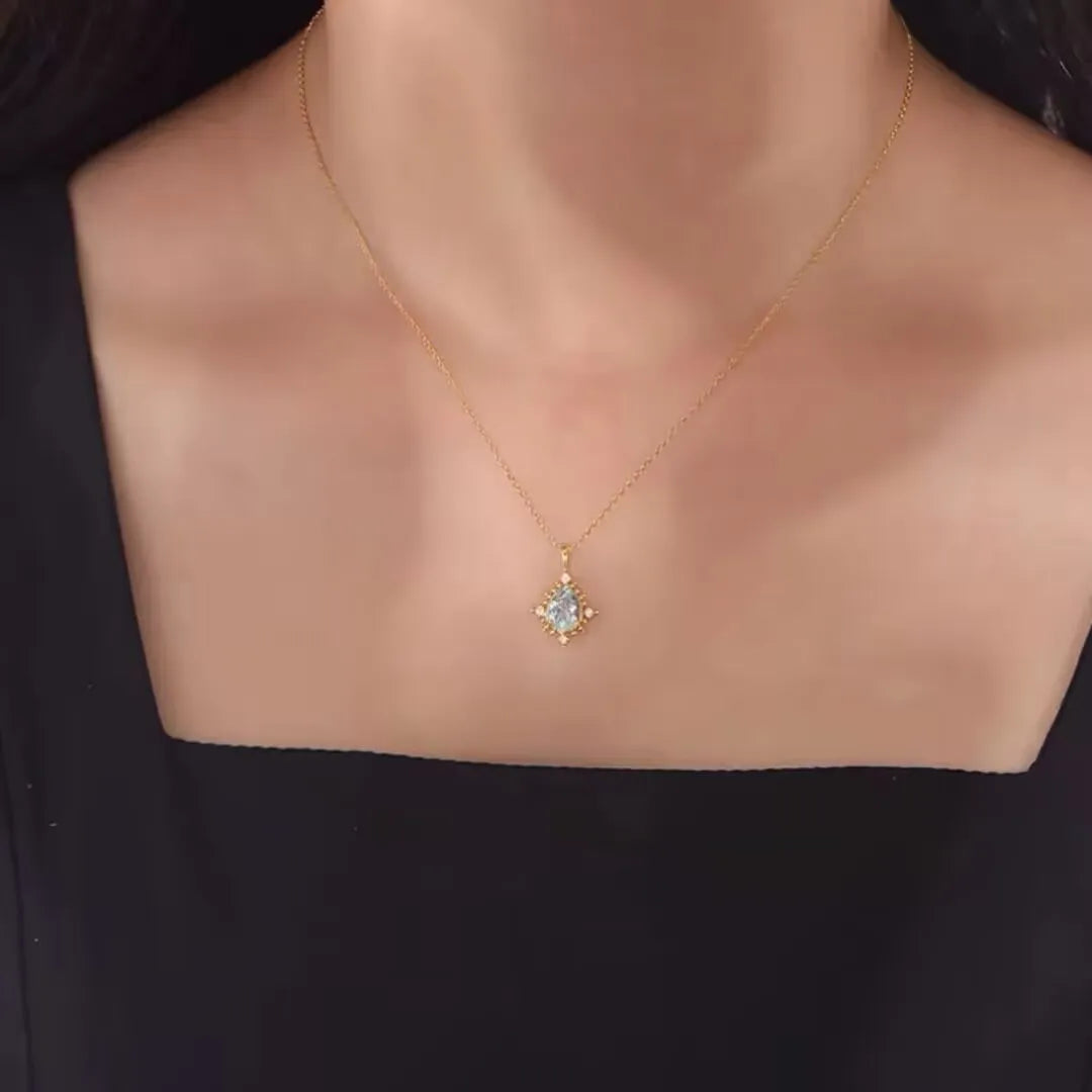 Collier Topaze "Rayons d'Élégance" en argent 925, avec une pierre centrale bleue pâle entourée de petits cristaux, sur un fond noir.