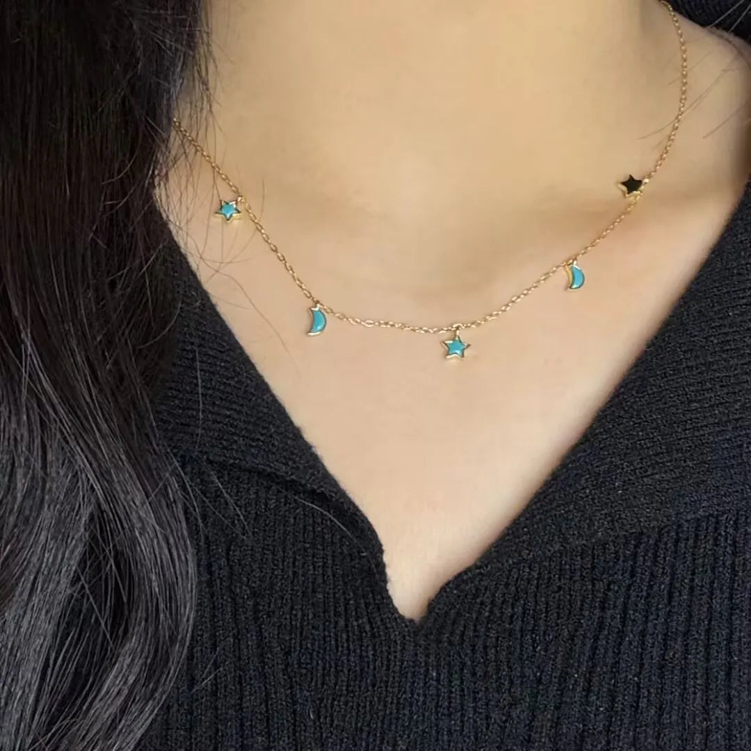 Collier "Équilibre Céleste" en argent doré or, orné de petites lunes et d'étoiles turquoise et d'une étoile noire.