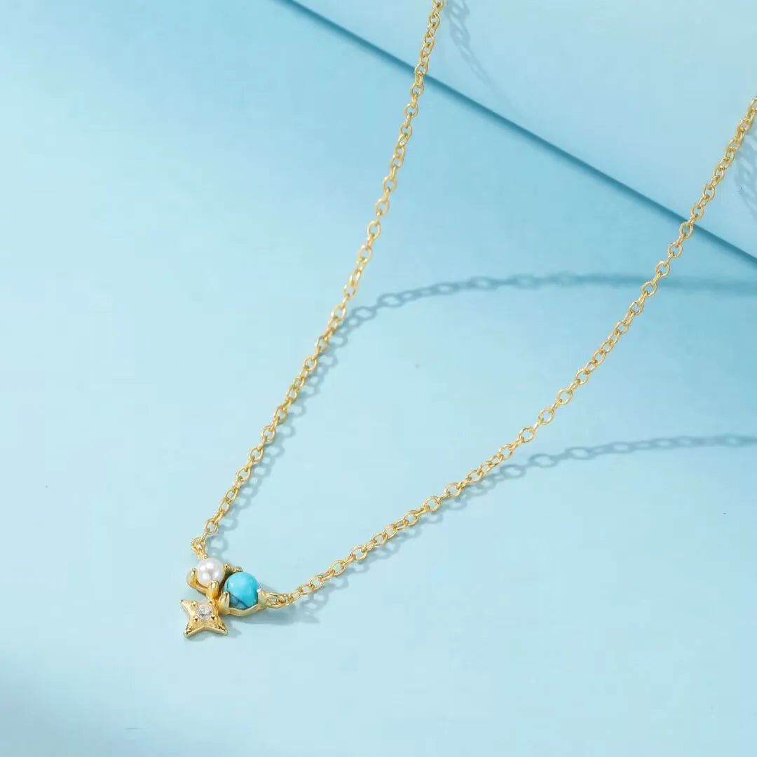 Collier "Sagesse Stellaire" en argent doré or, orné d'une turquoise, d'une perle blanche et d'une petite étoile scintillante.