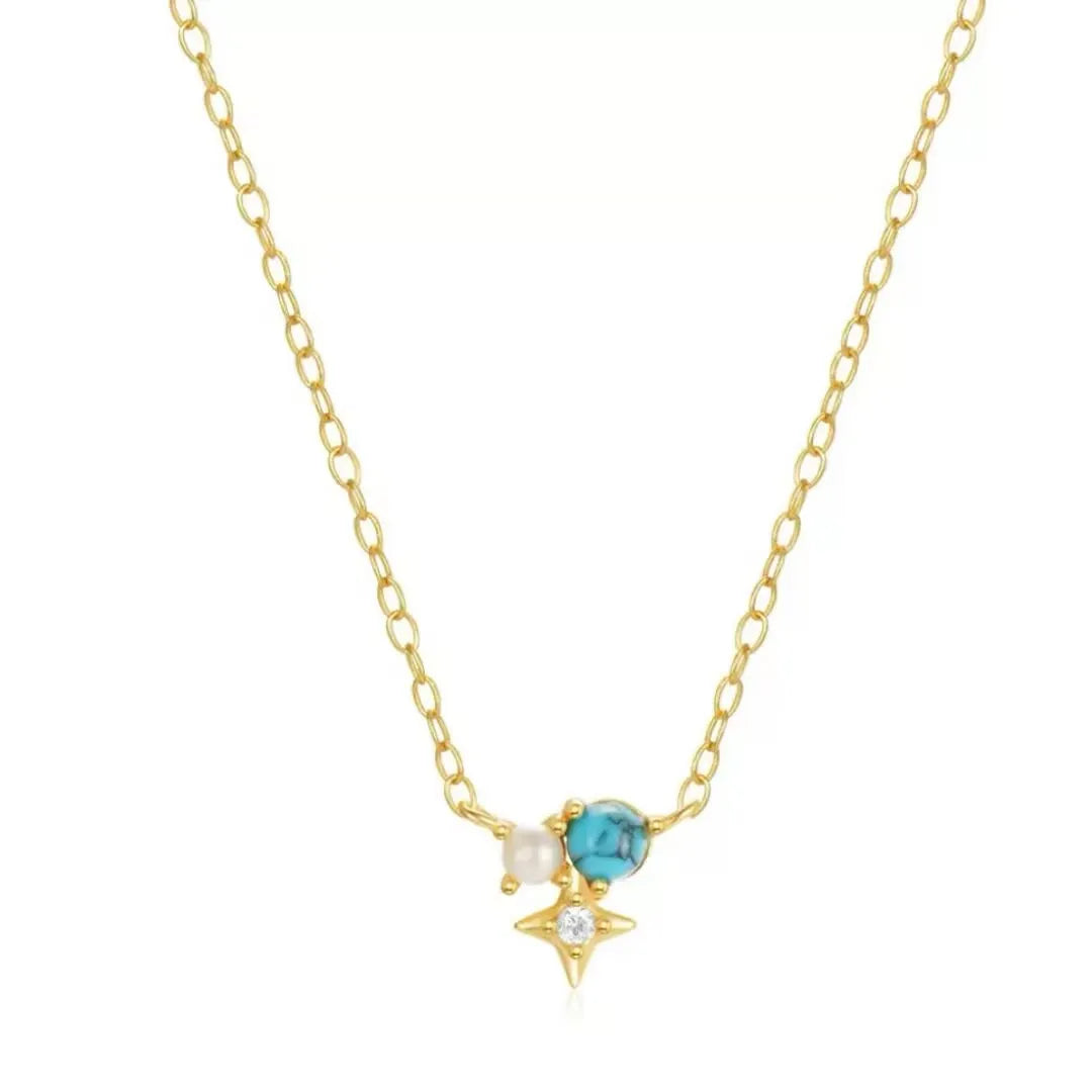 Collier fin en argent doré or, orné d'une petite perle blanche, d'une turquoise bleue et d'un éclat de zircone en forme d'étoile, le tout suspendu à une chaîne délicate.