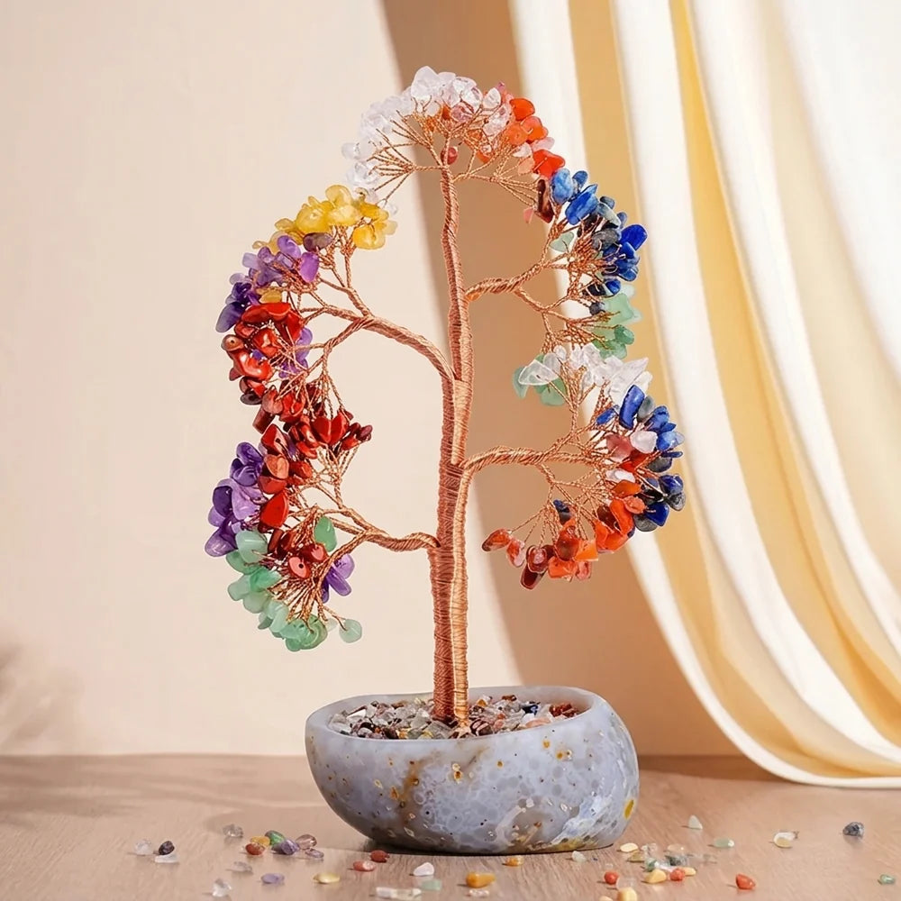 Arbre de vie artisanal aux 7 chakras, avec des pierres colorées en guise de feuilles et un tronc en fil de cuivre, posé dans un pot en pierre naturelle.
