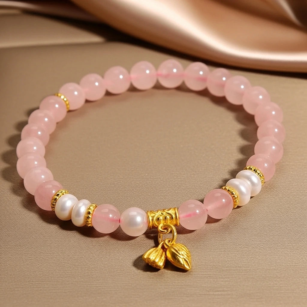 Bracelet fait de perles rondes en quartz rose, alternant avec des perles d'eau douce et des éléments dorés, orné d'un pendentif en forme de feuilles dorées.