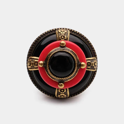 Bague "Merveille d'Antan" avec une agate noire centrale, un cercle rouge et des détails dorés sur fond gris.