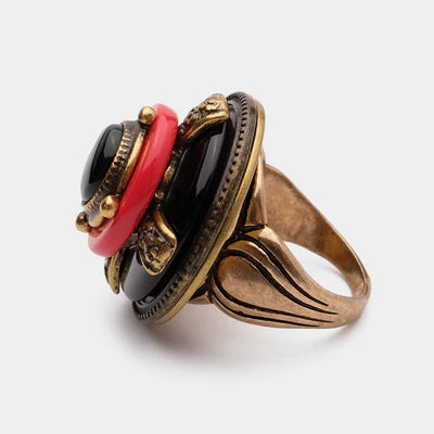 Bague "Merveille d'Antan" en laiton doré vieilli avec une grande agate noire facettée, entourée d'un anneau rouge et de détails dorés sculptés rappelant une fleur.