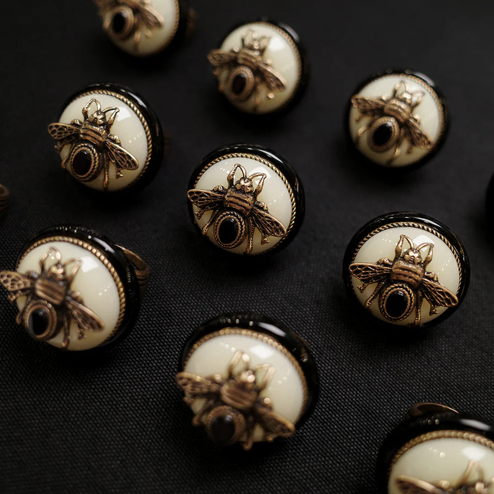 Bague "Reine Noire" en argent avec une tête d'abeille dorée ornée d'une petite pierre noire et un cabochon en agate noire sur fond noir.