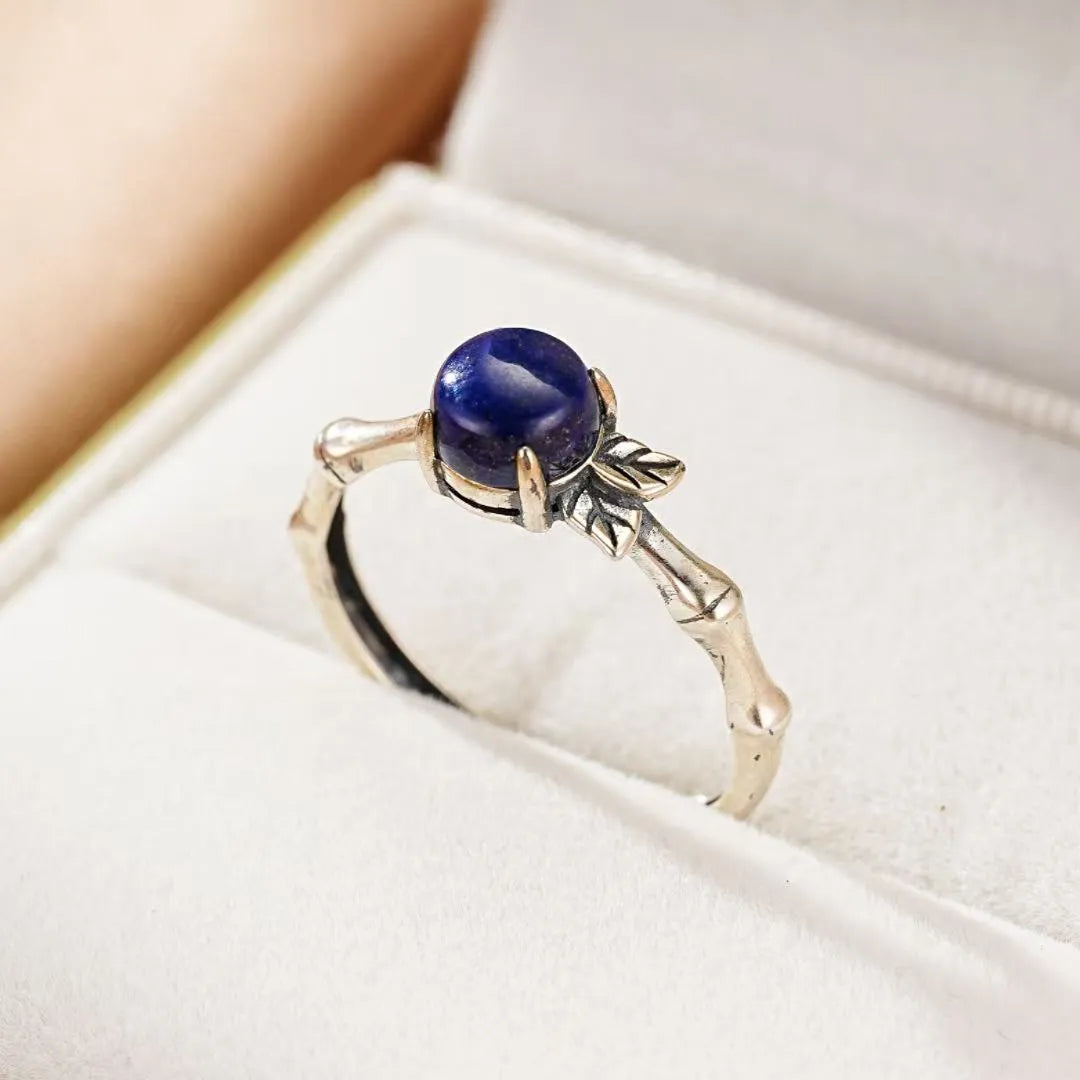 Bague "Éclat de Nature" en argent avec un lapis lazuli bleu profond, design inspiré de la nature avec une monture en forme de branche de bambou et des feuilles délicates.