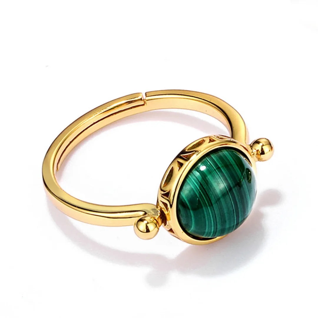 Bague ajustement en argent doré or avec une pierre de malachite ovale au centre, sertie dans un entourage gravé de motifs anciens.